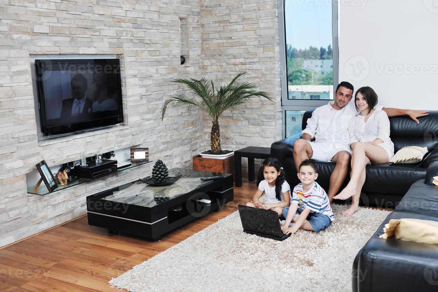 une jeune famille heureuse s'amuse et travaille sur un ordinateur portable à la maison photo