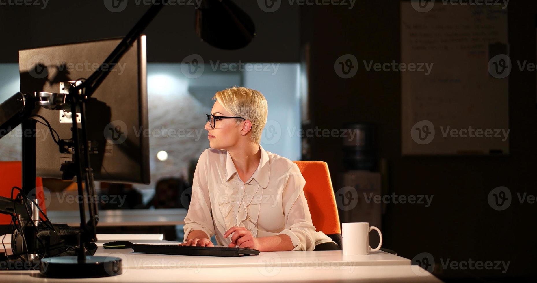 femme travaillant sur ordinateur dans un bureau sombre photo