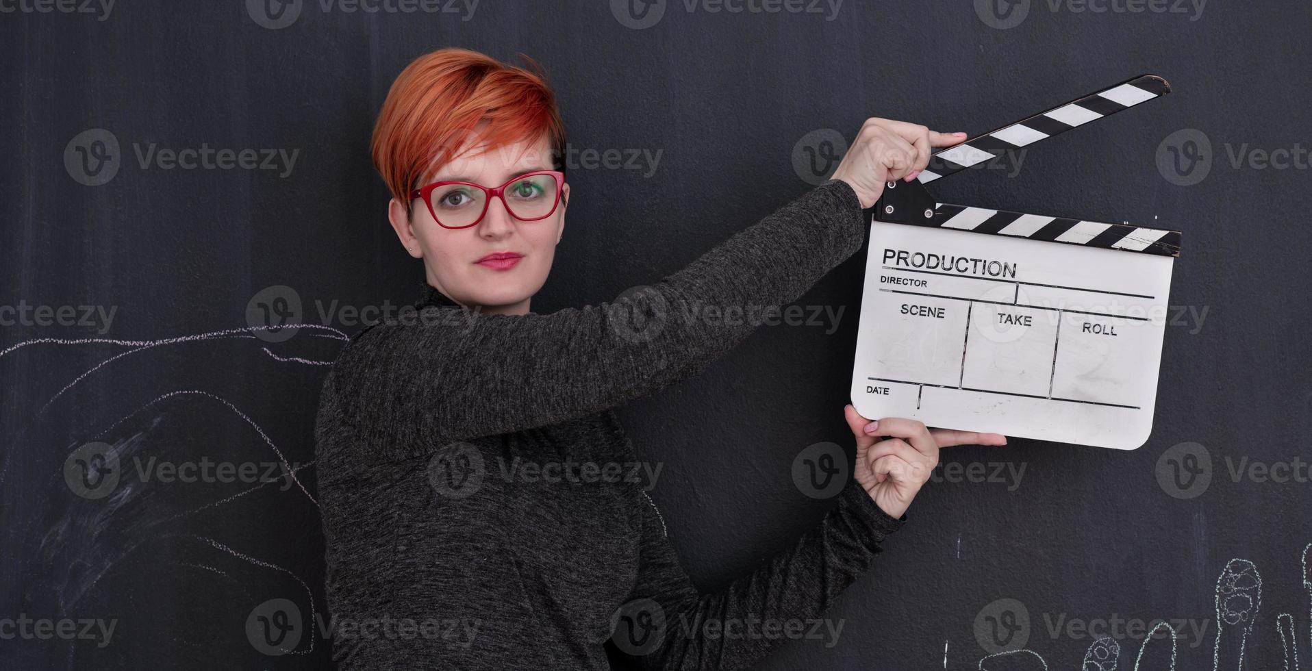 Redhead woman holding clapper sur fond noir photo