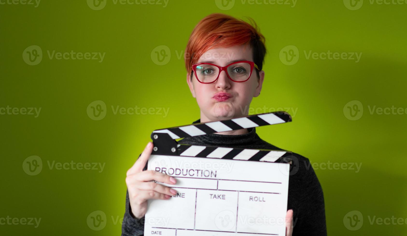 redhead woman holding movie clapper sur fond vert photo