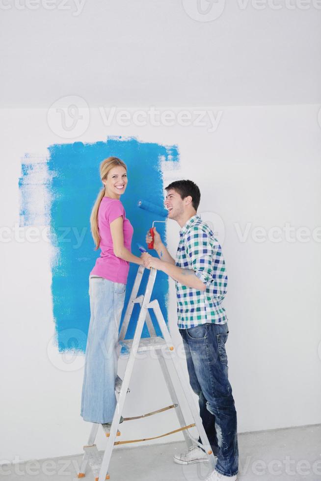 couple heureux peindre un mur dans une nouvelle maison photo