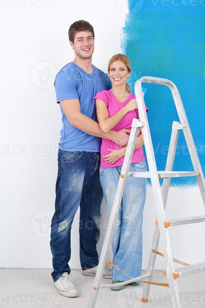 couple heureux peindre un mur dans une nouvelle maison photo