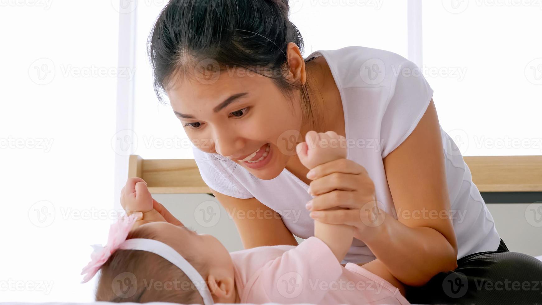 jeune mère avec son petit bébé jouant sur le lit à la maison. photo