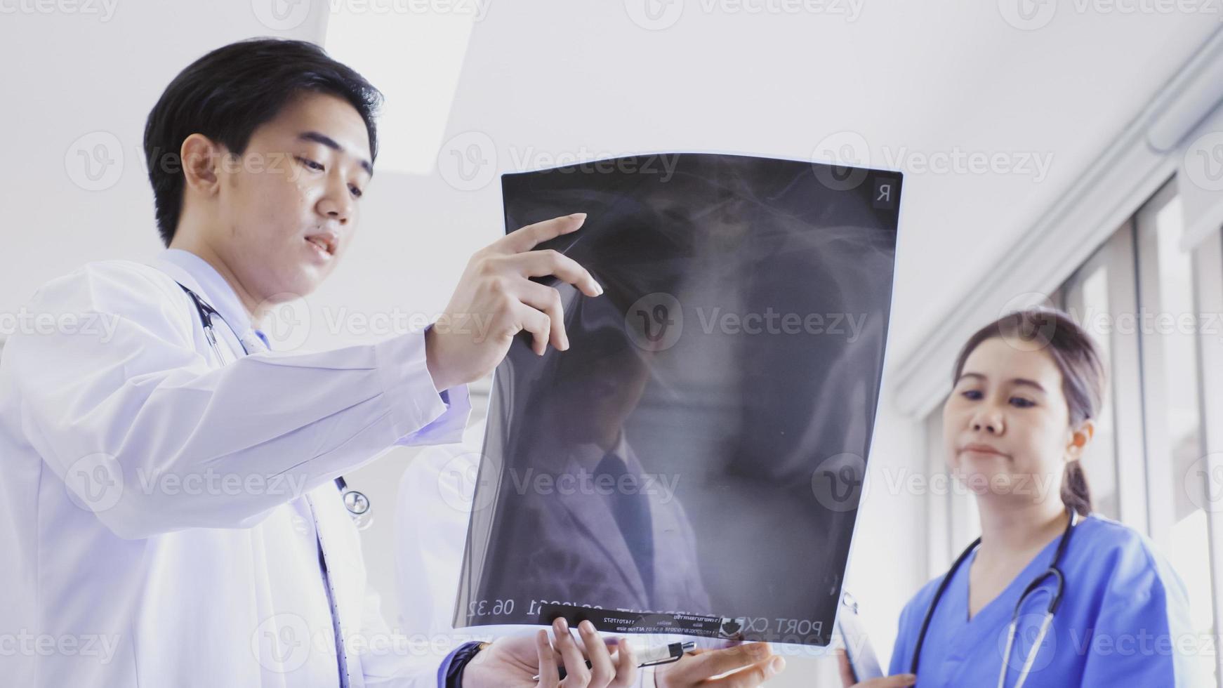 médecin et assistants médicaux discutant du résultat du diagnostic sur un film radiographique. photo