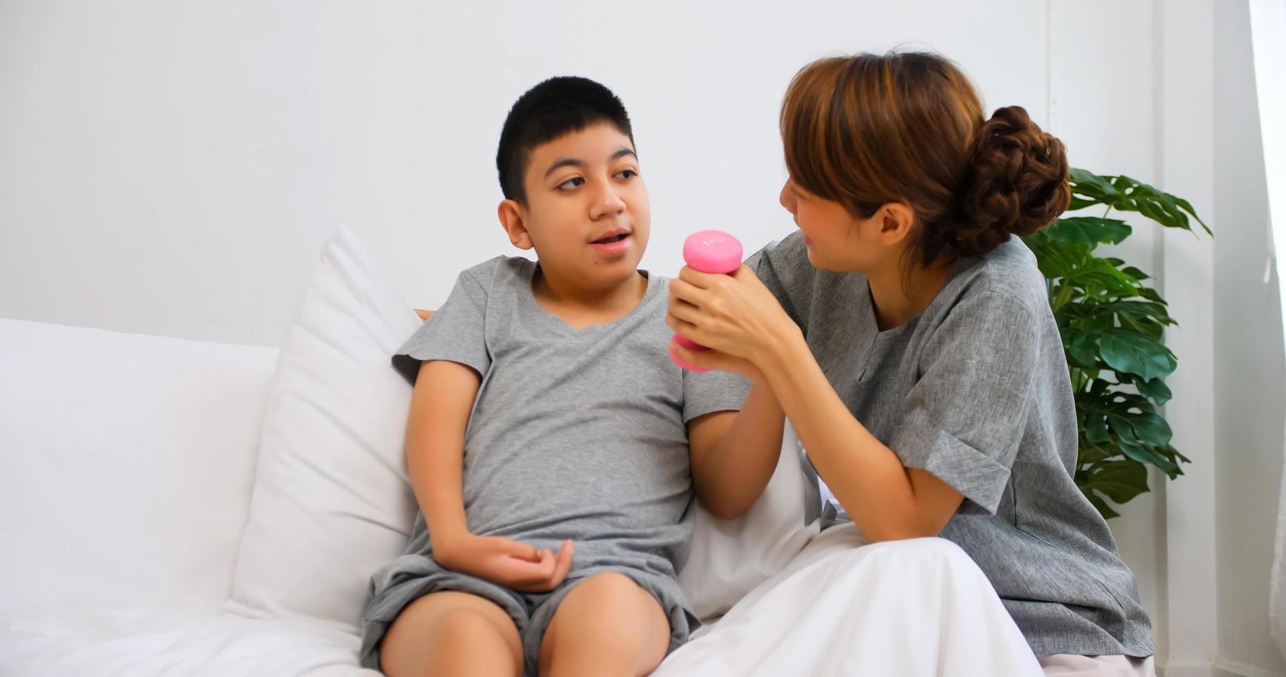 le fils handicapé suit une thérapie en faisant de l'exercice avec le soutien et les soins de sa mère. photo