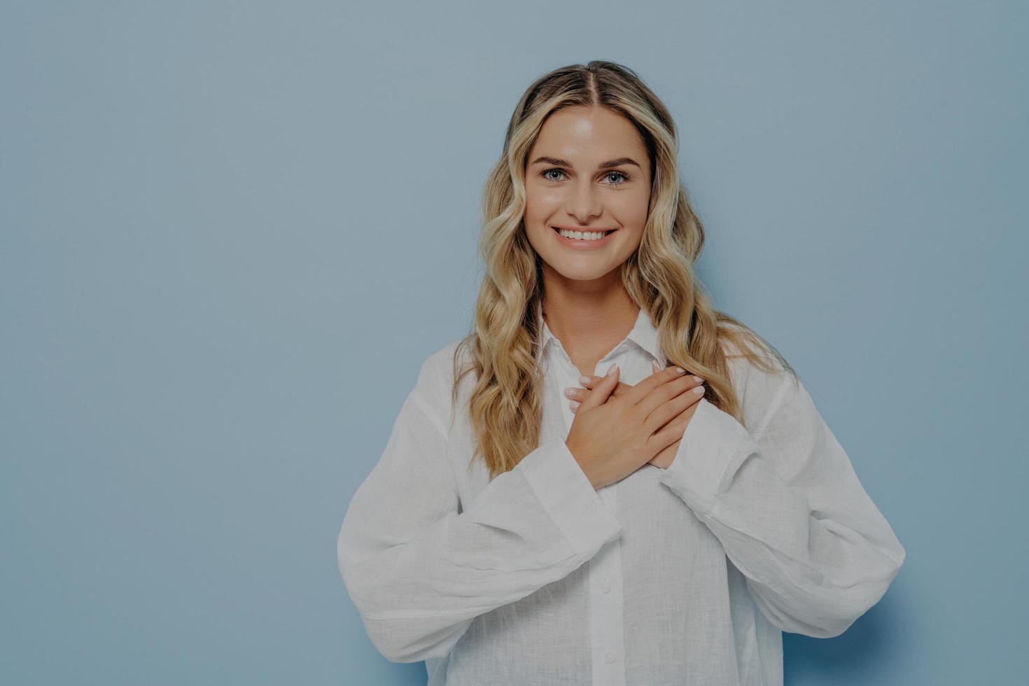 femme blonde soulagée avec les mains sur sa poitrine photo