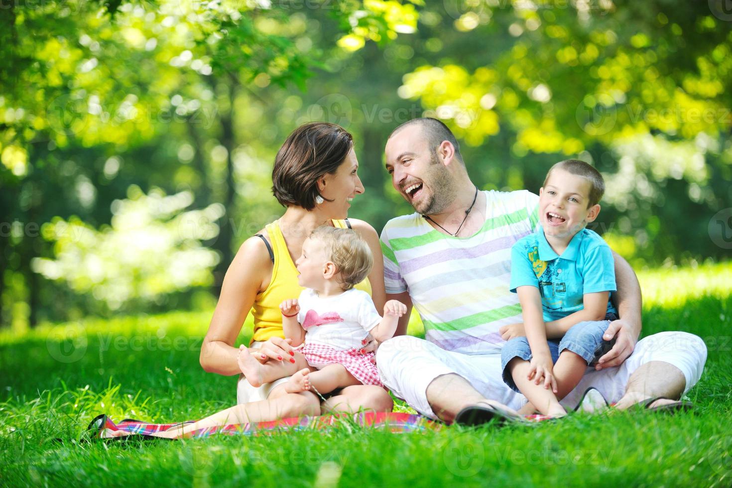 heureux jeune couple avec leurs enfants s'amuser au parc photo