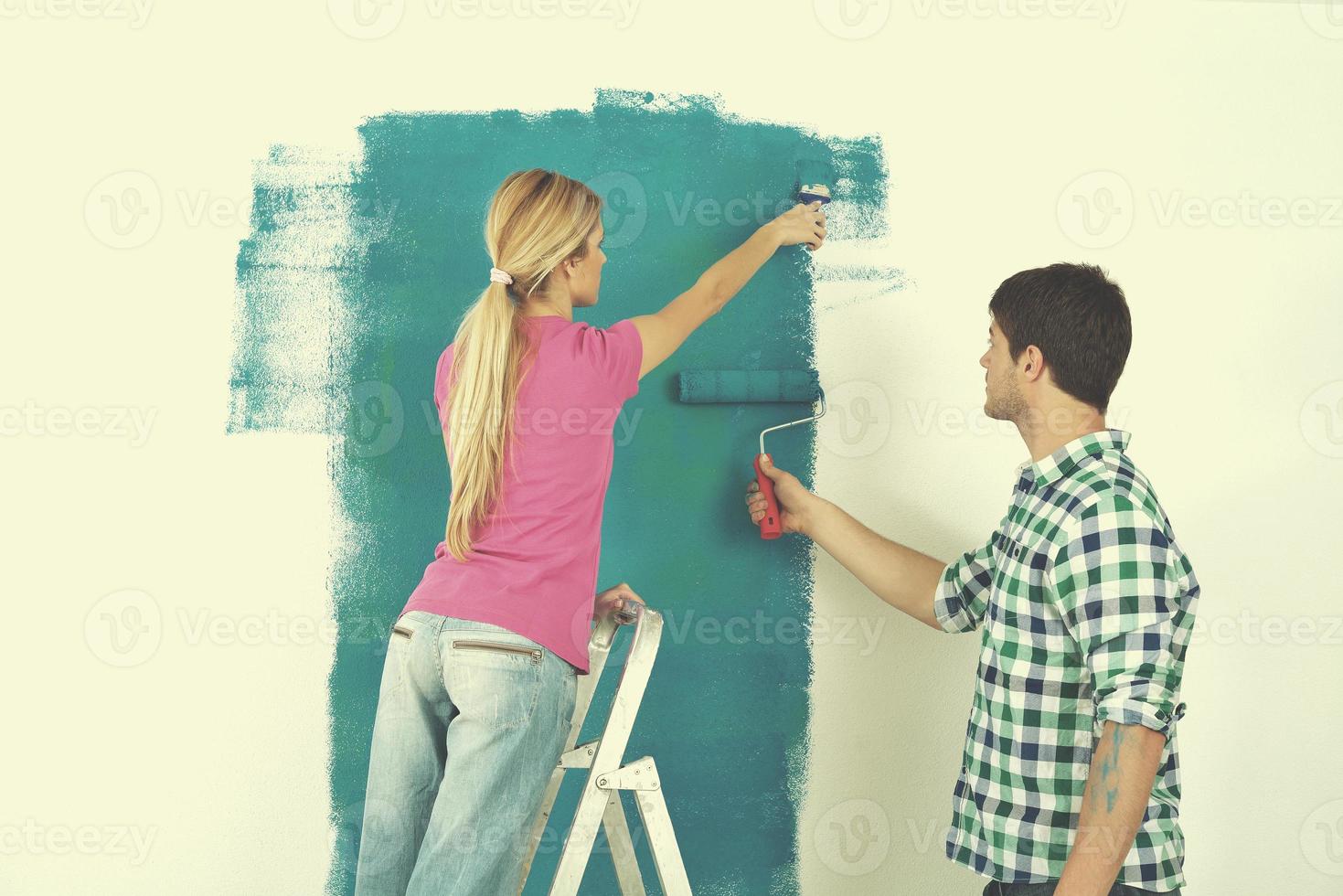 couple heureux peindre un mur dans une nouvelle maison photo