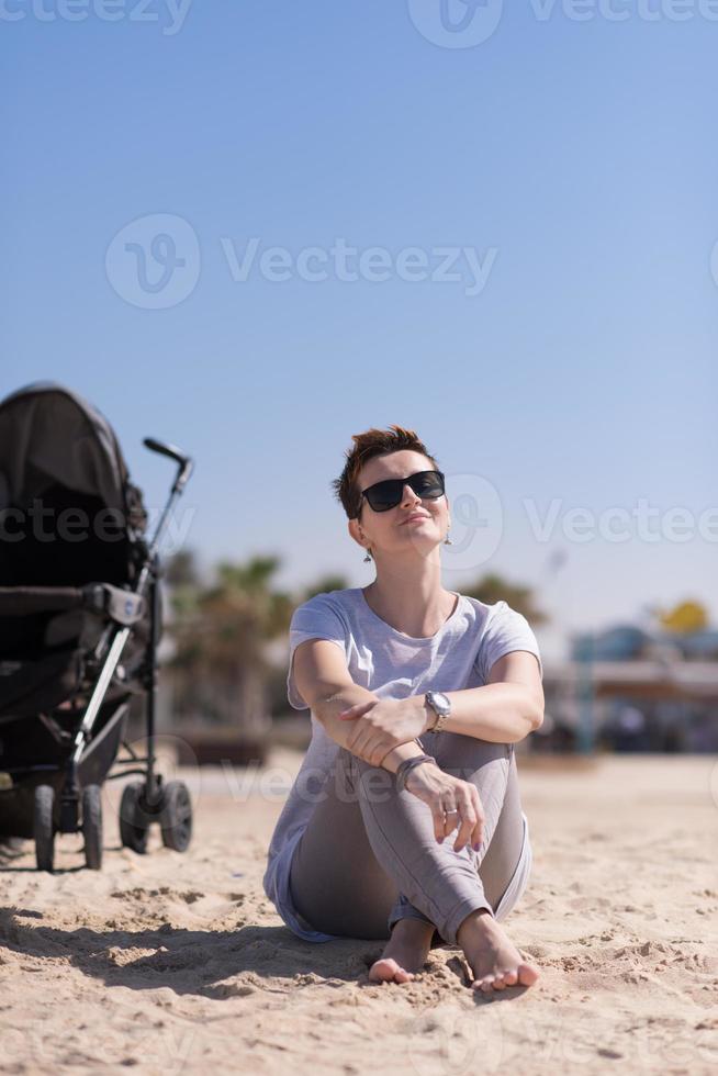 jeune mère avec des lunettes de soleil relaxantes sur la plage photo