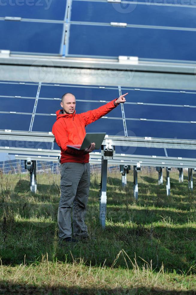 ingénieur utilisant un ordinateur portable sur le terrain de l'usine de panneaux solaires photo