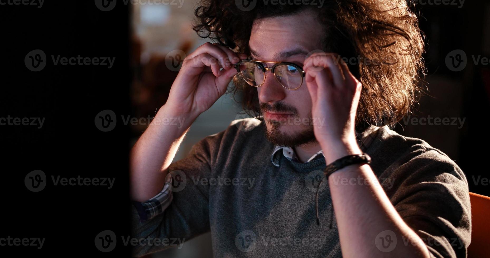 homme travaillant sur ordinateur dans un bureau sombre photo