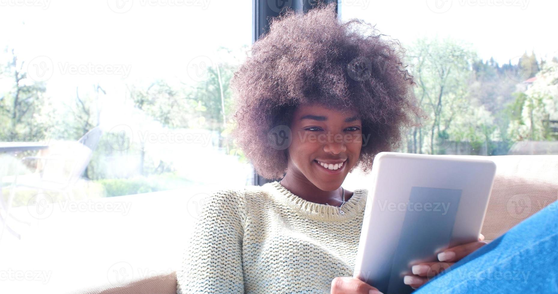 femme afro-américaine à la maison à l'aide d'une tablette numérique photo