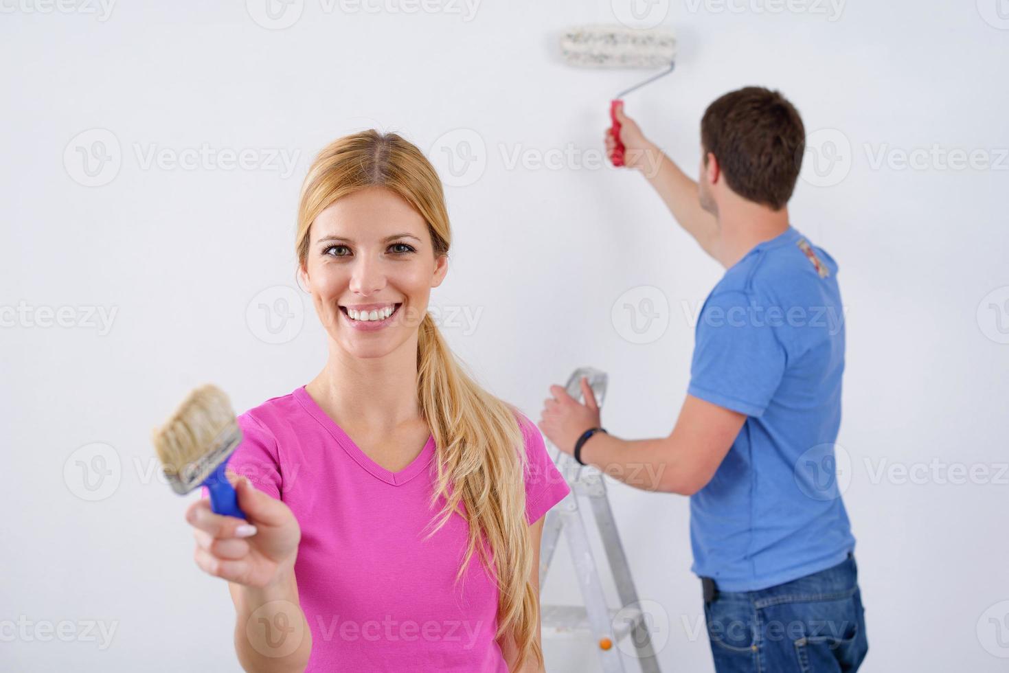 couple heureux peindre un mur dans une nouvelle maison photo