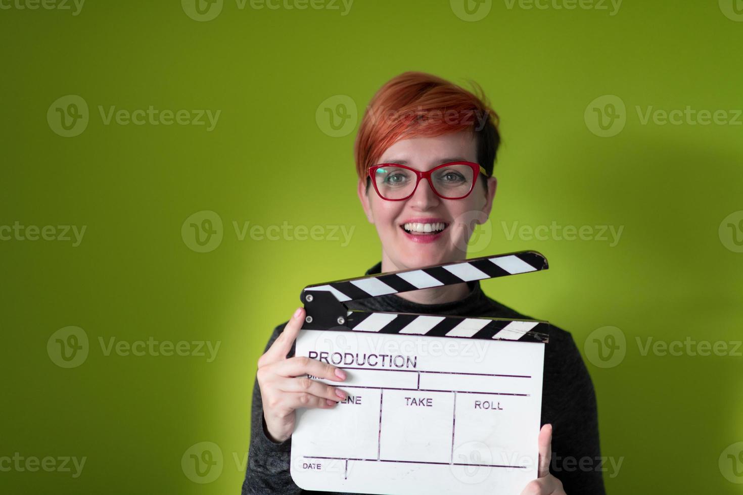 redhead woman holding movie clapper sur fond vert photo