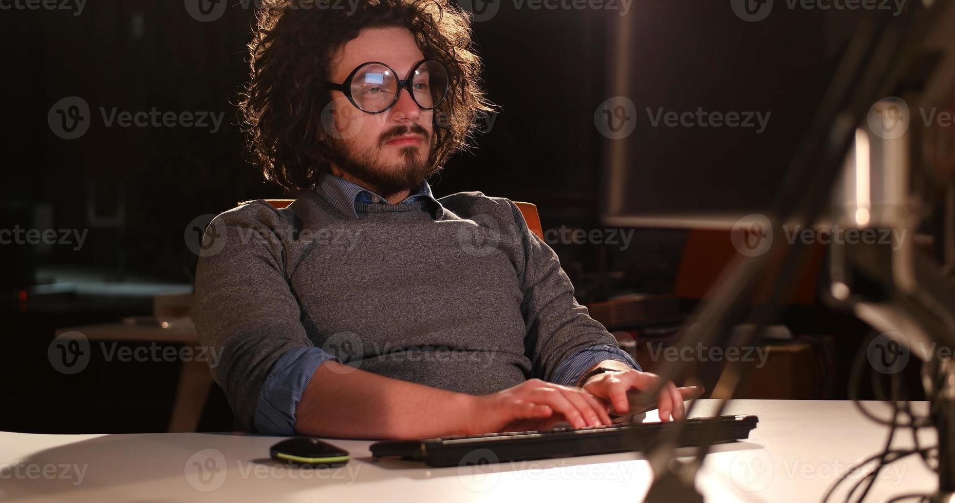 homme travaillant sur ordinateur dans un bureau sombre photo