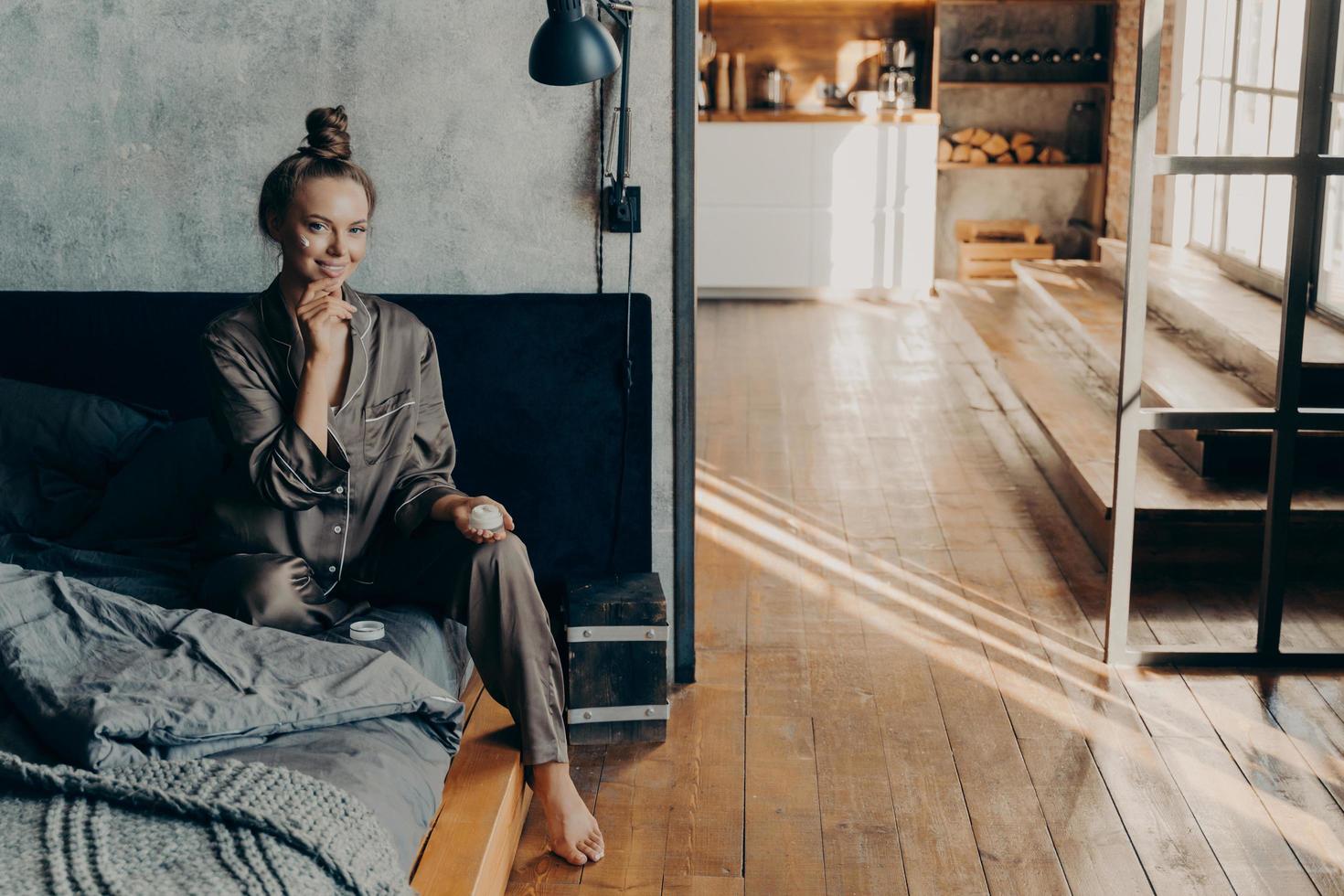 jeune belle fille est assise sur le lit en pyjama après s'être réveillée photo