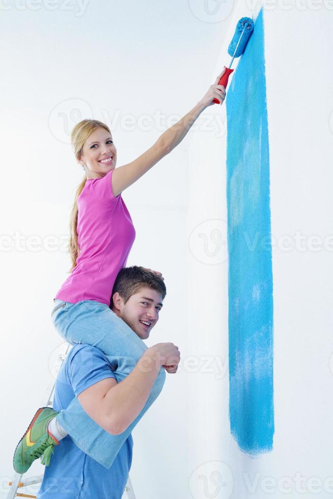 couple heureux peindre un mur dans une nouvelle maison photo