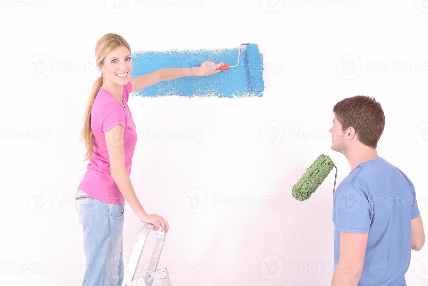 couple heureux peindre un mur dans une nouvelle maison photo