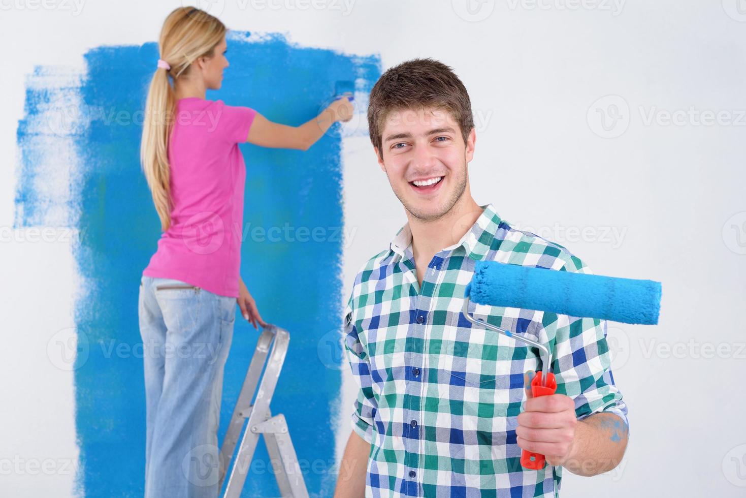 couple heureux peindre un mur dans une nouvelle maison photo