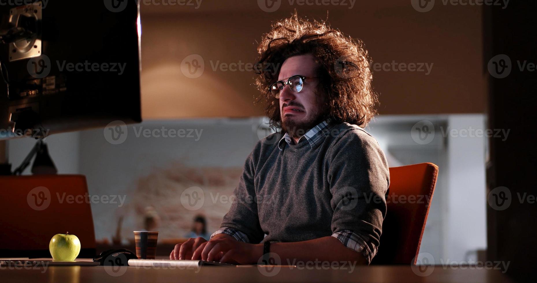 homme travaillant sur ordinateur dans un bureau sombre photo