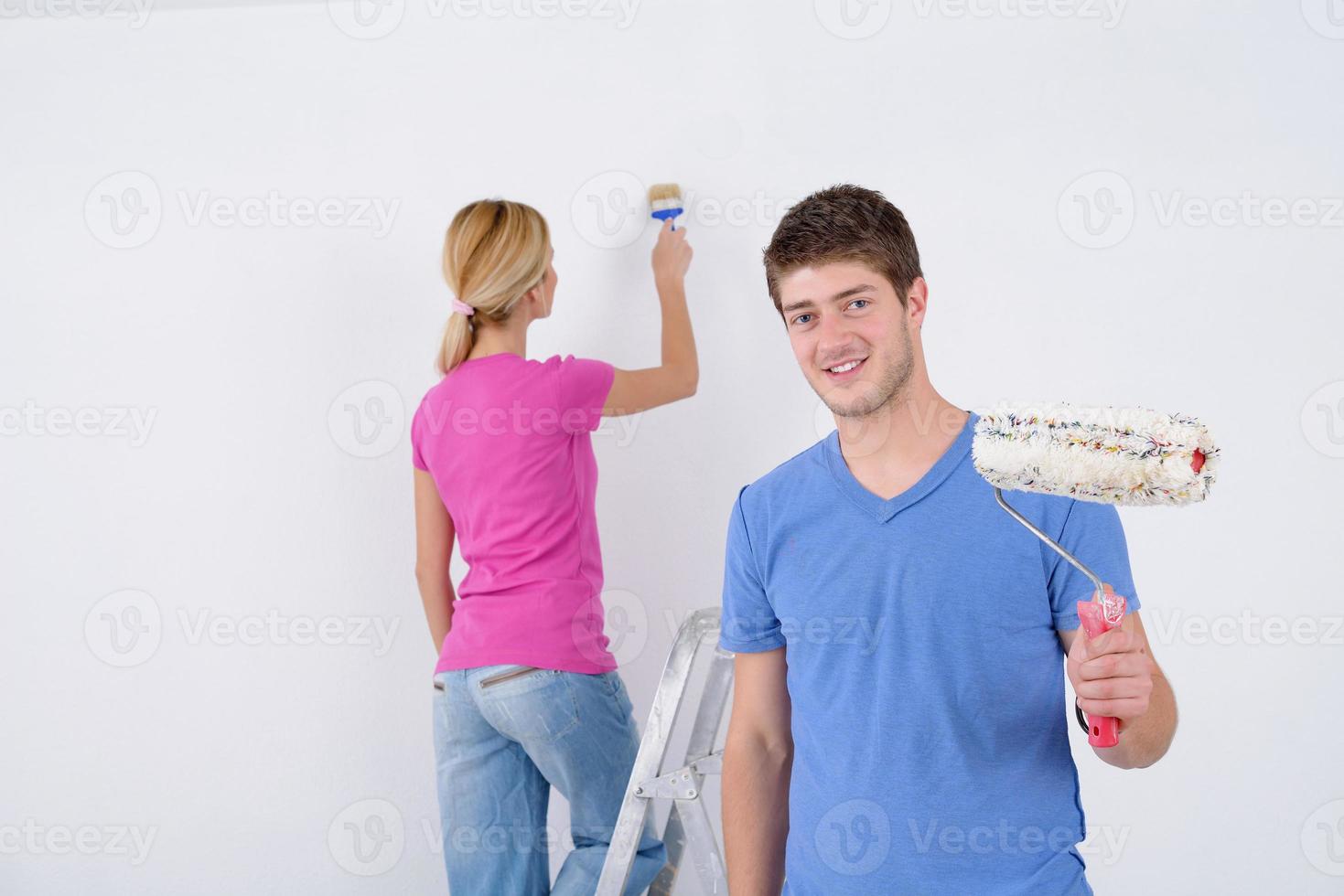 couple heureux peindre un mur dans une nouvelle maison photo