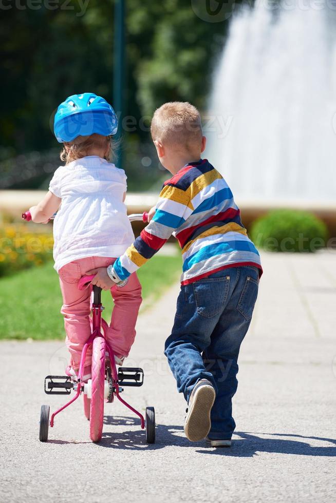 garçon et fille dans le parc apprenant à faire du vélo photo