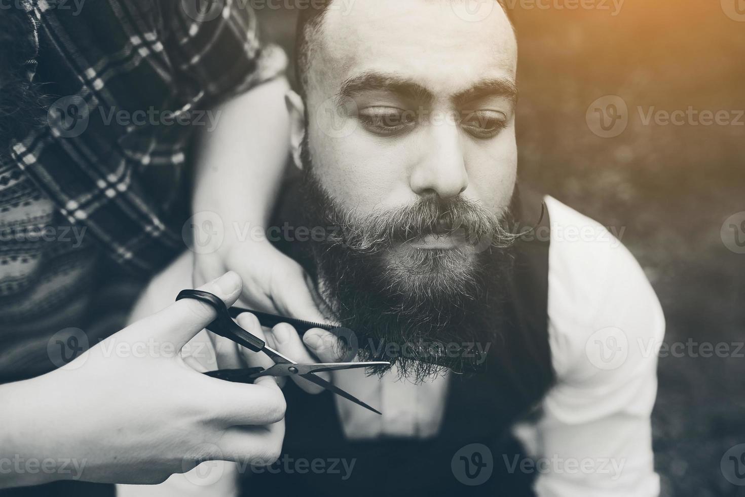 coiffeur rase un homme barbu dans une atmosphère vintage photo