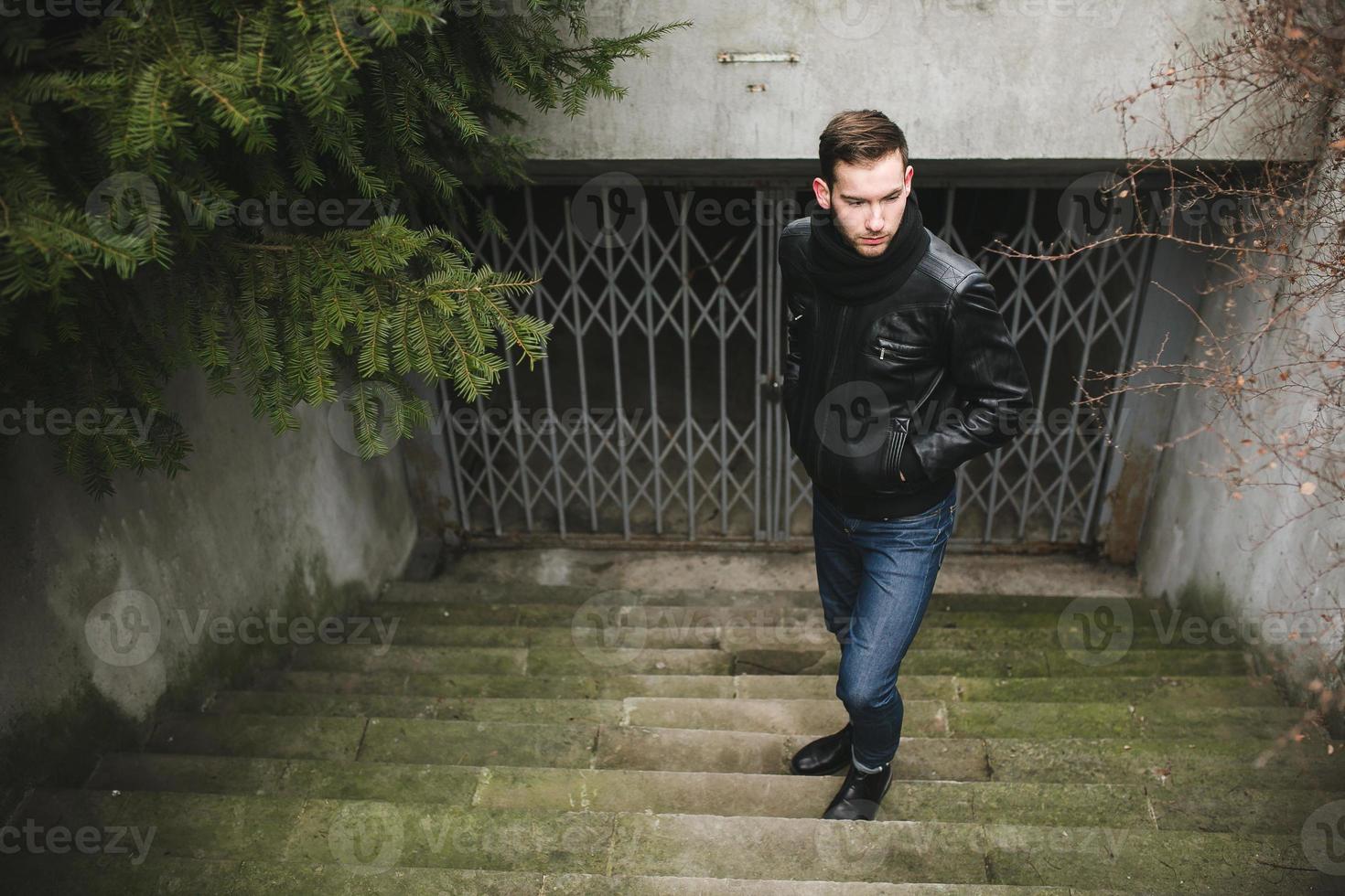 un homme vêtu d'un jean et d'une veste noire sur des escaliers authentiques photo