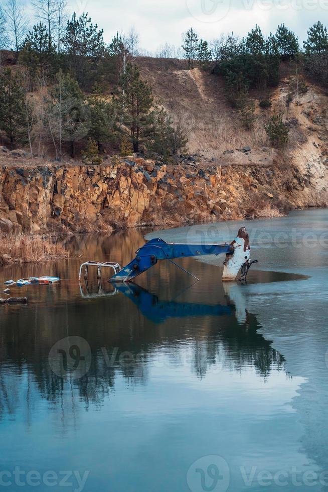 excavatrice inondée dans un grand lac près de la carrière basaltique photo