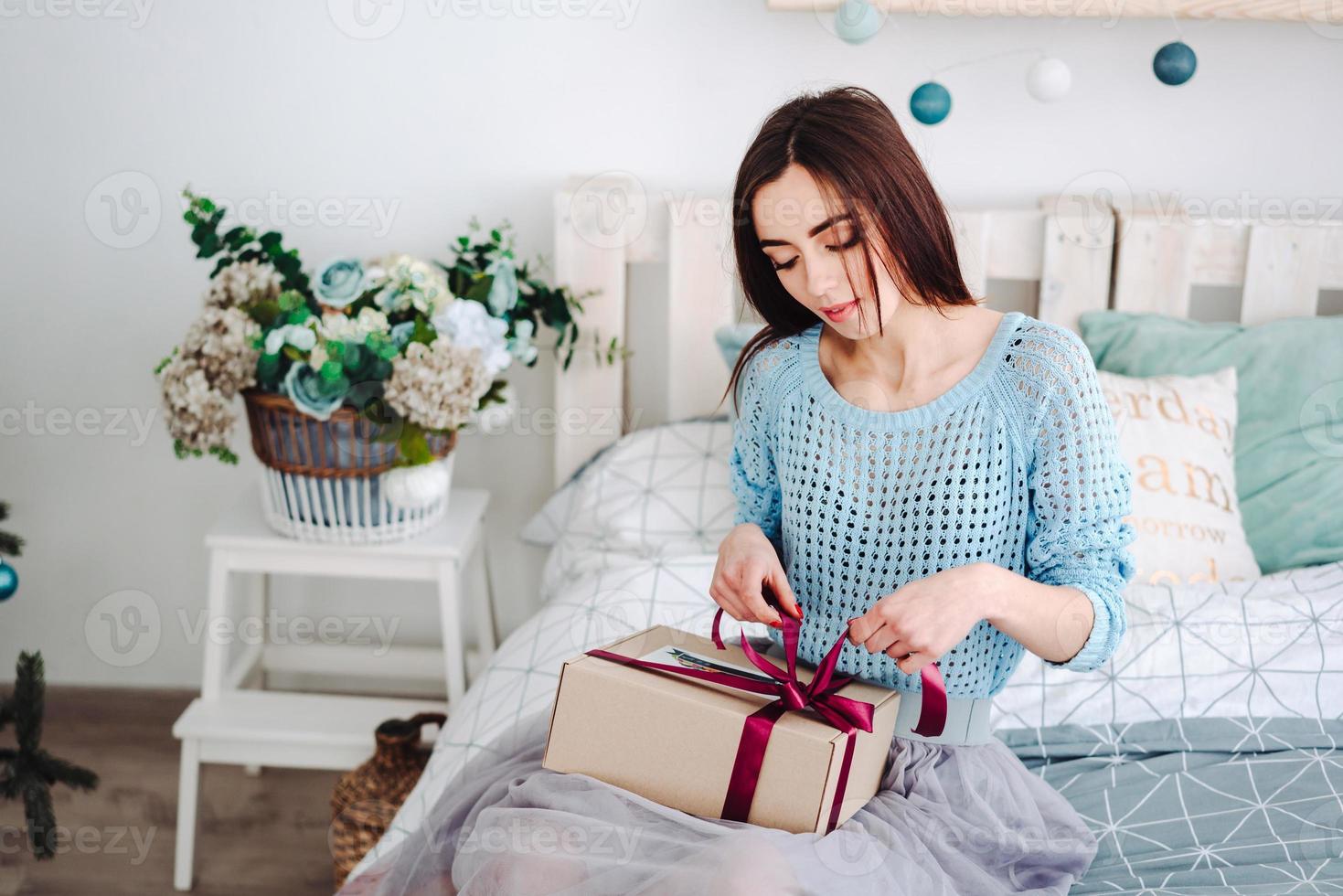 fille assise dans son lit avec boîte cadeau photo