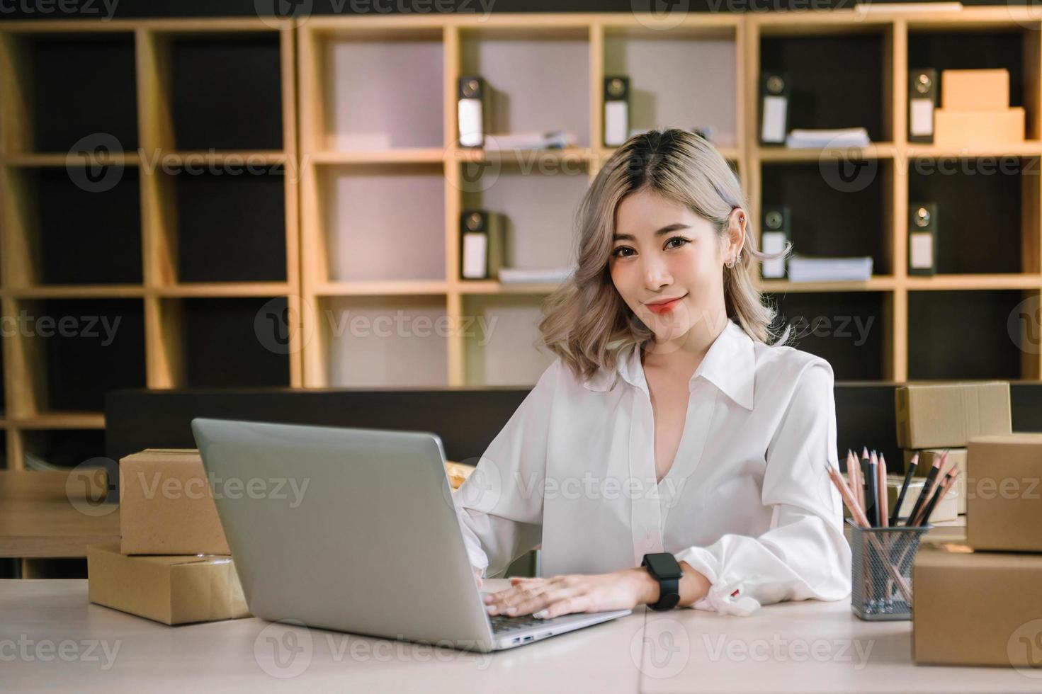 main de femme utilisant un ordinateur portable, un smartphone et une tablette et un cahier d'écriture au bureau de ses achats en ligne d'entreprise. à la maison photo