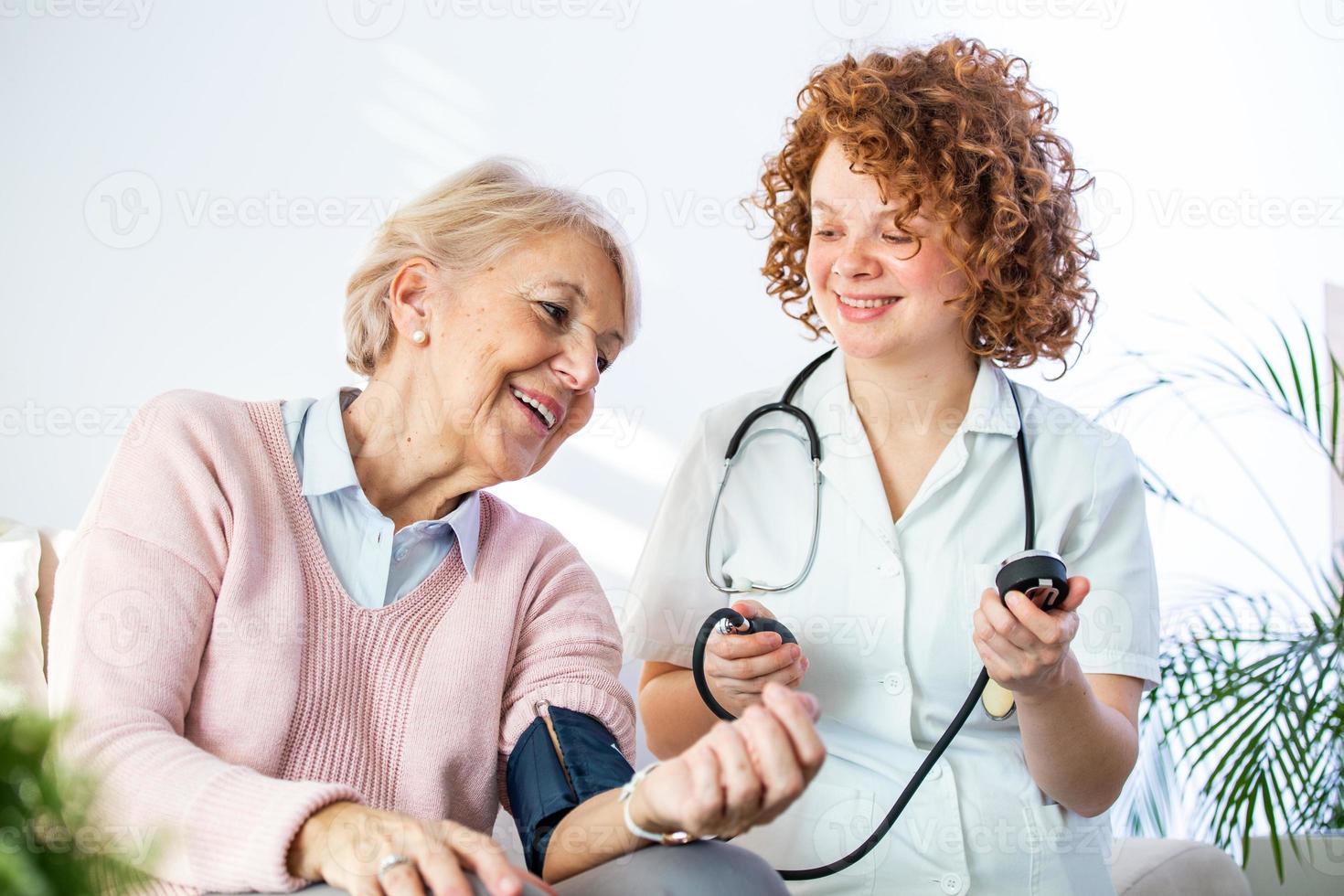 jeune infirmière mesurant la pression artérielle d'une femme âgée à la maison. infirmière vérifiant la pression artérielle d'une femme âgée à la maison, soignant à domicile vérifiant la pression artérielle des patients photo