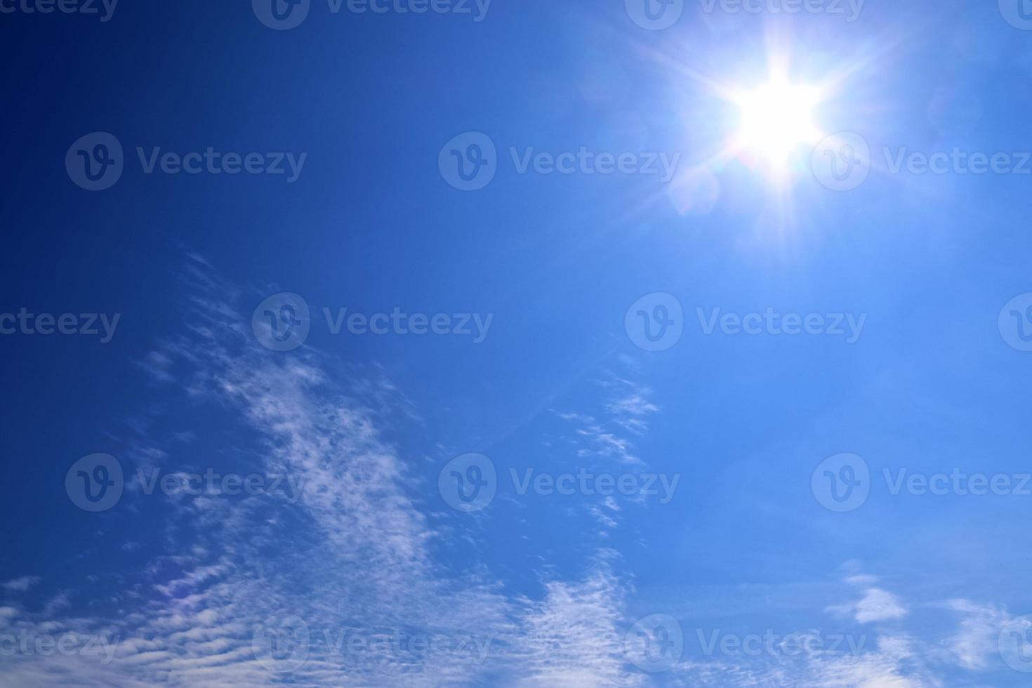 belle vue sur les rayons du soleil avec quelques reflets et nuages dans un ciel bleu photo