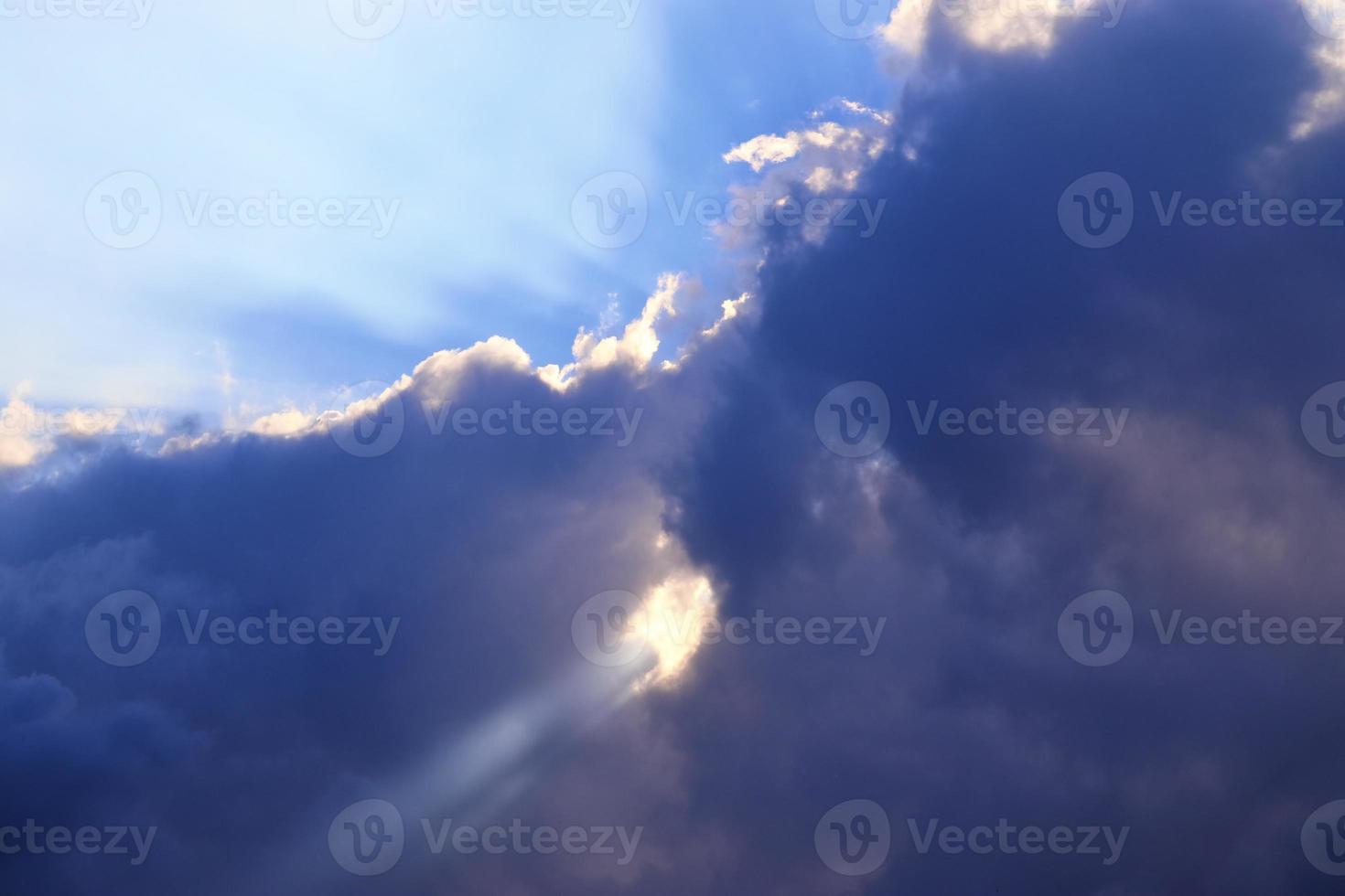 belle vue sur les rayons du soleil avec quelques reflets et nuages dans un ciel bleu photo