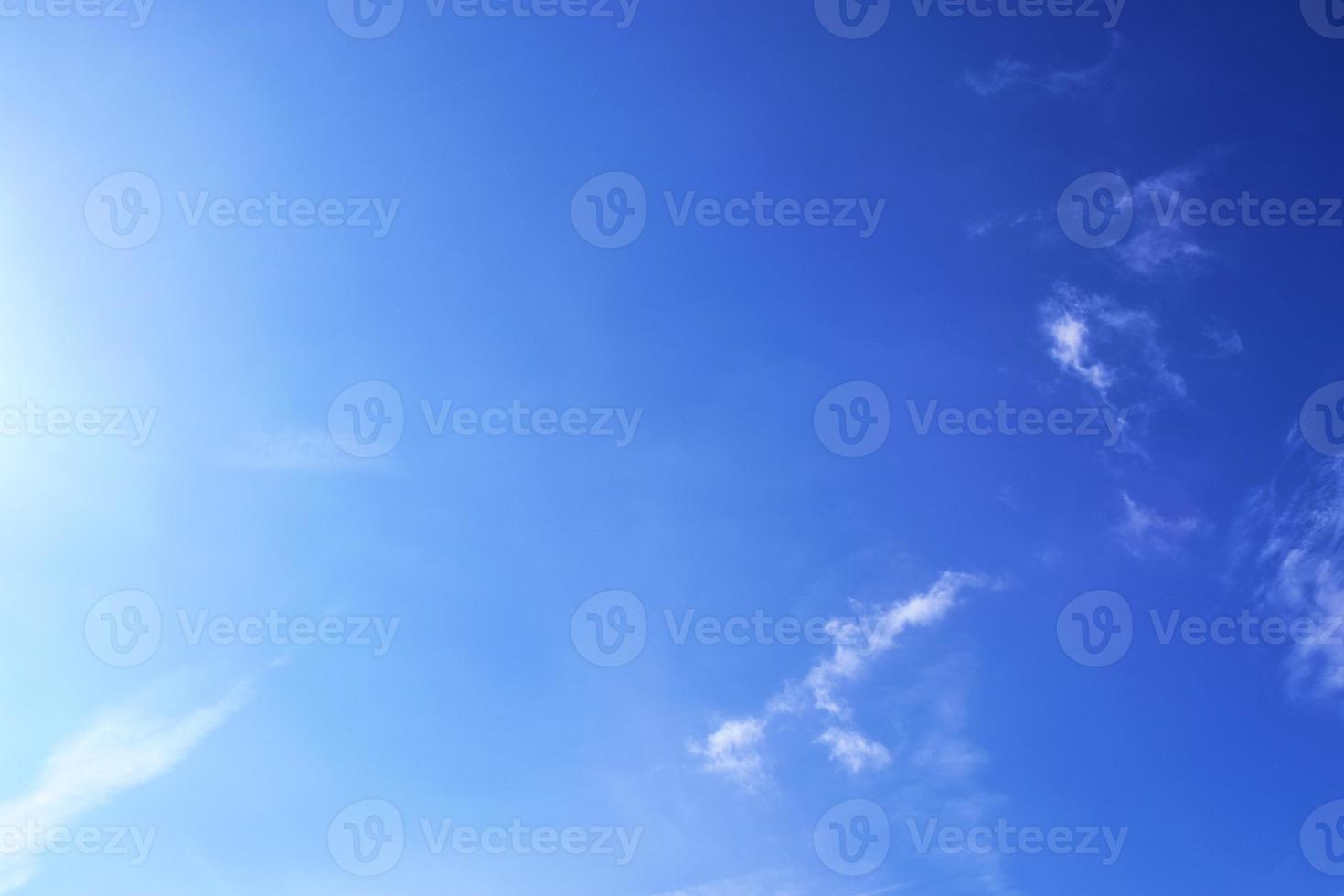 belle vue sur les rayons du soleil avec quelques reflets et nuages dans un ciel bleu photo