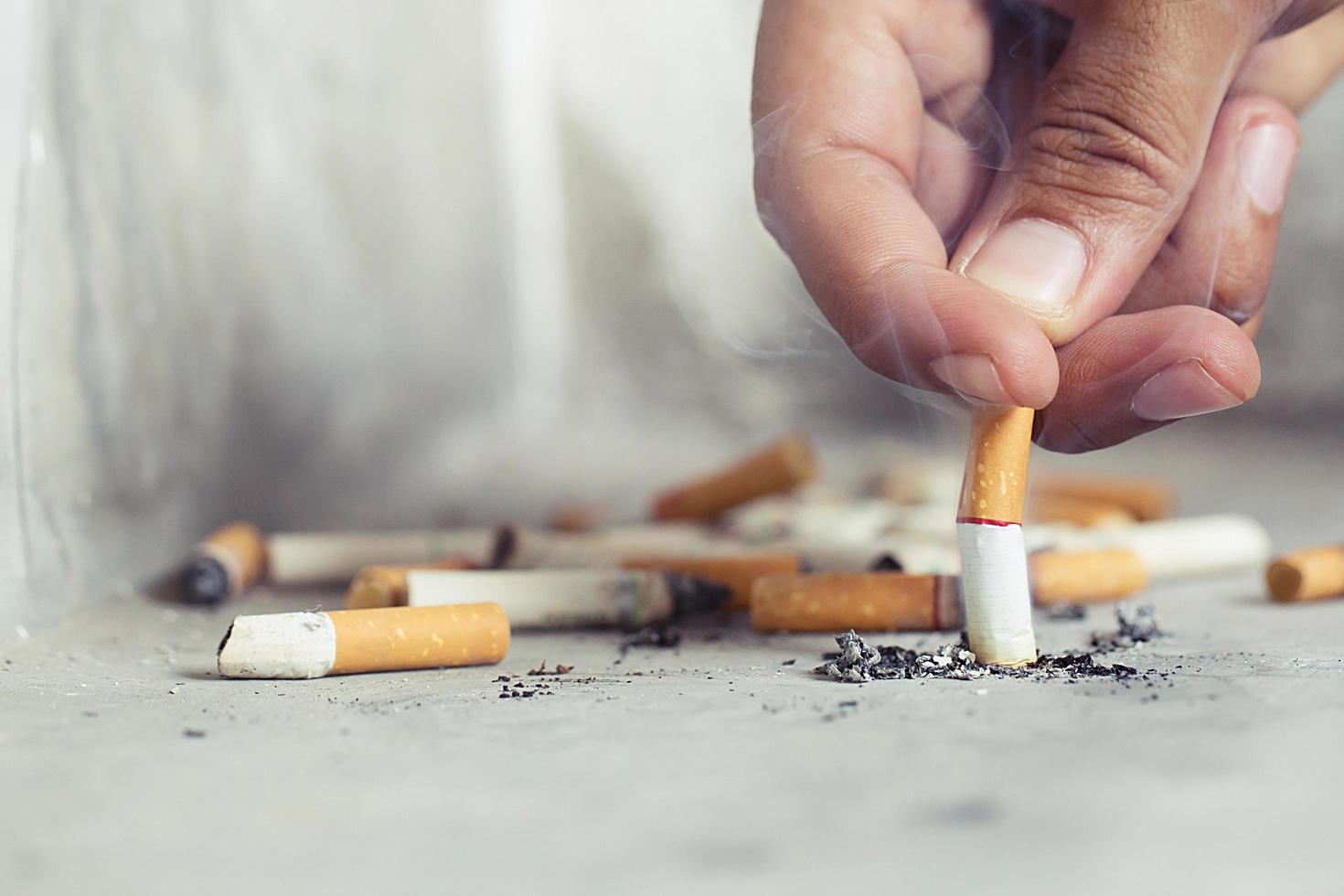 main éteignant une cigarette, mégot de cigarette sur sol en béton, ciment nu. photo