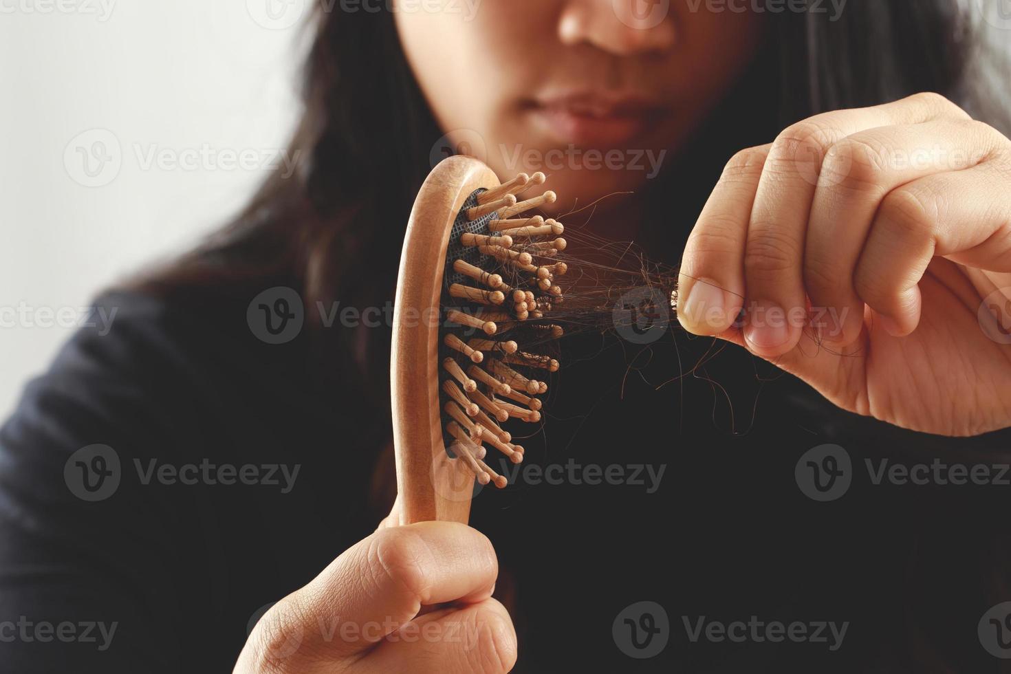 vue arrière jeune femme inquiète du problème de perte de cheveux, du déséquilibre hormonal, du concept de stress. beaucoup de cheveux tombent après avoir peigné la brosse à cheveux à la main. femme démêlé ses cheveux avec un peigne, soins de santé photo