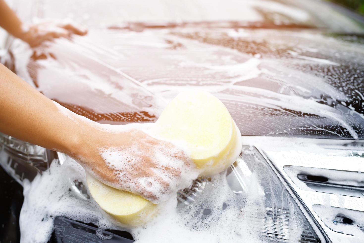 personnes travailleur homme tenant la main éponge jaune et fenêtre nettoyante en mousse à bulles pour laver la voiture. concept de lavage de voiture propre. laisser de la place pour écrire des messages. photo