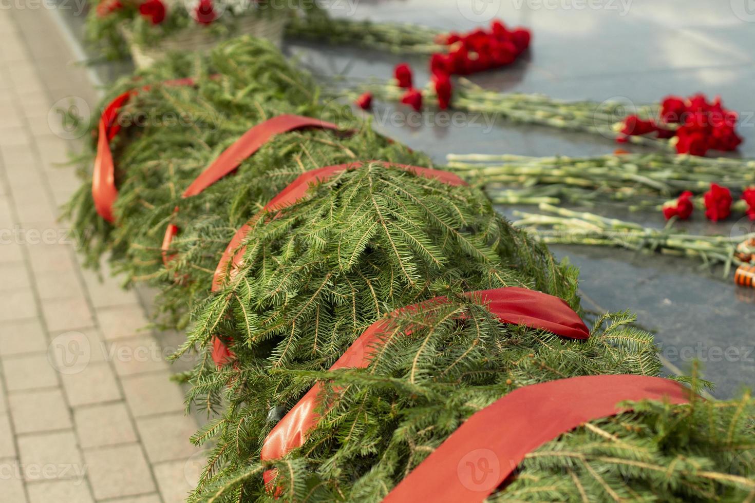 couronnes d'épicéa sur le monument. rubans rouges commémoratifs sur la tombe d'un soldat. plantes symboliques sur le site de la victoire dans la grande guerre patriotique. photo