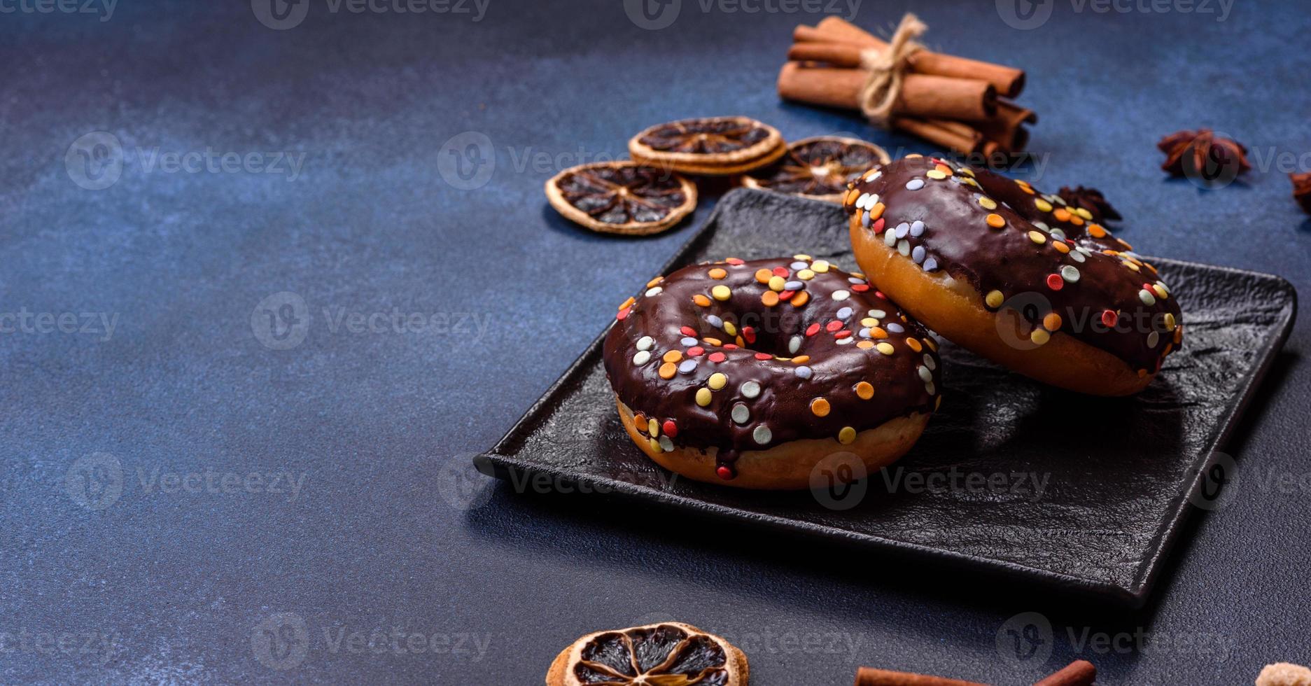 notion de pâtisseries. beignets au glaçage au chocolat avec pépites, sur une table en béton foncé photo