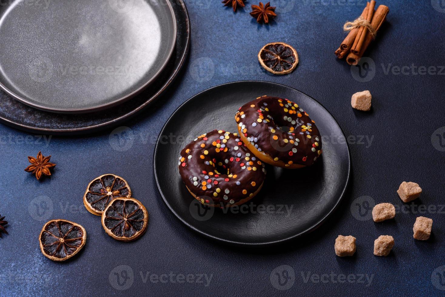 notion de pâtisseries. beignets au glaçage au chocolat avec pépites, sur une table en béton foncé photo