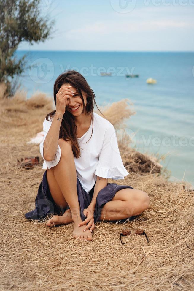 jolie femme en jupe et chemise d'été est assise sur le rivage photo