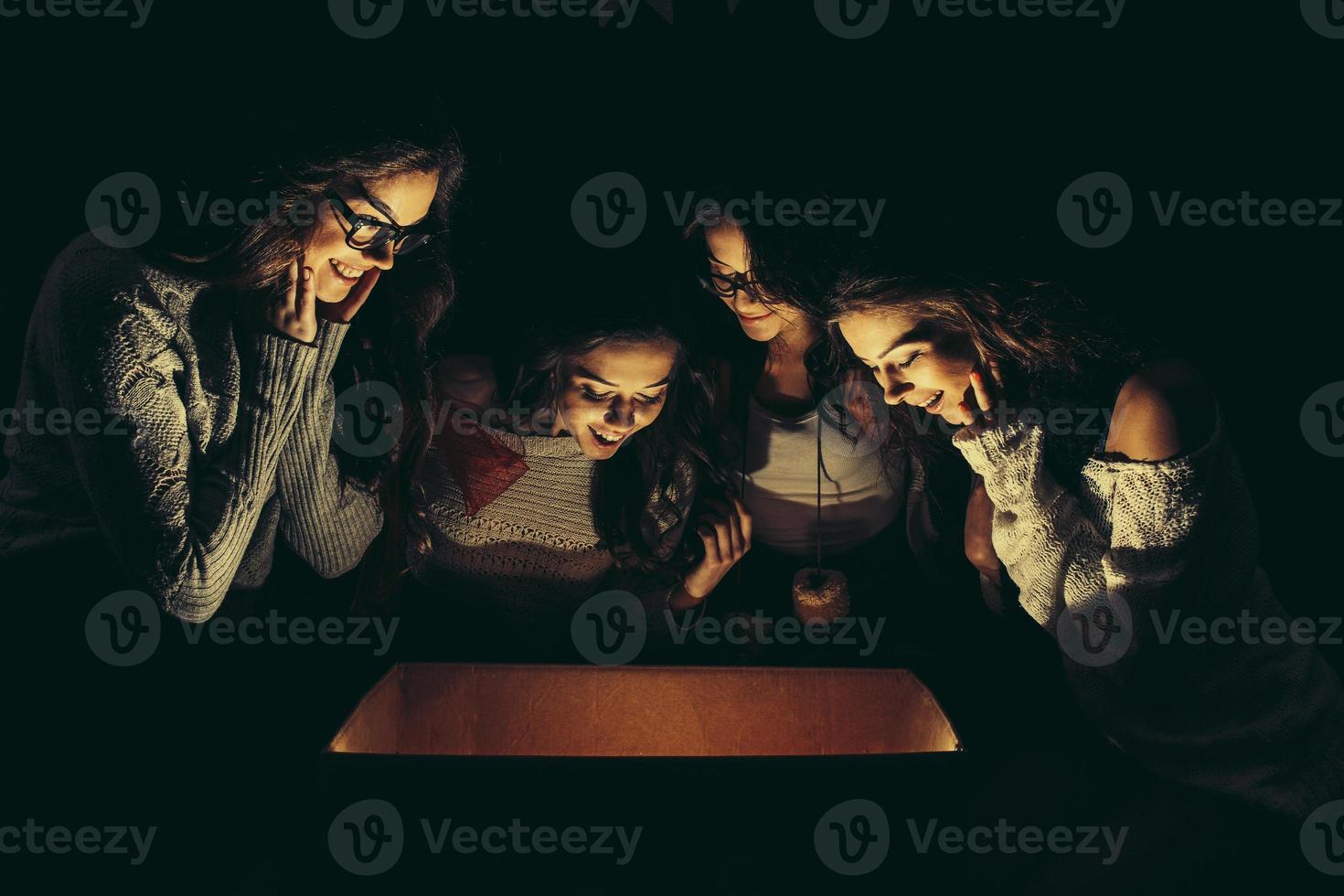 les soeurs ouvrent une boîte avec un cadeau de noël et des regards fascinés à l'intérieur photo