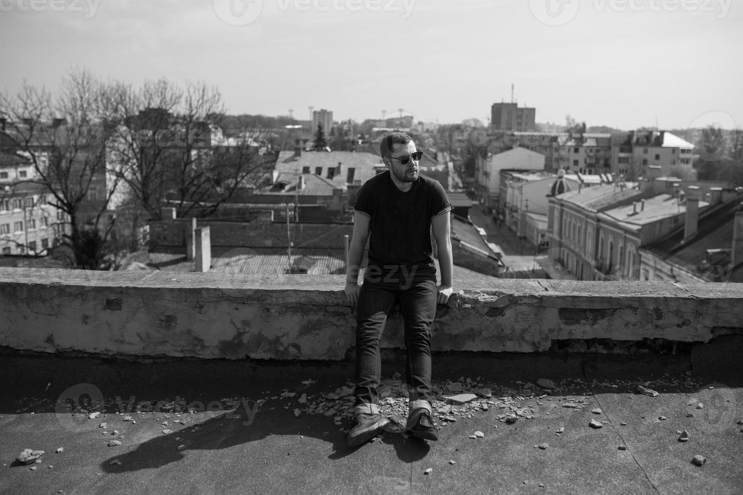 l'homme aux authentiques bottes et jeans lisière sur le toit de l'immeuble de la vieille ville photo