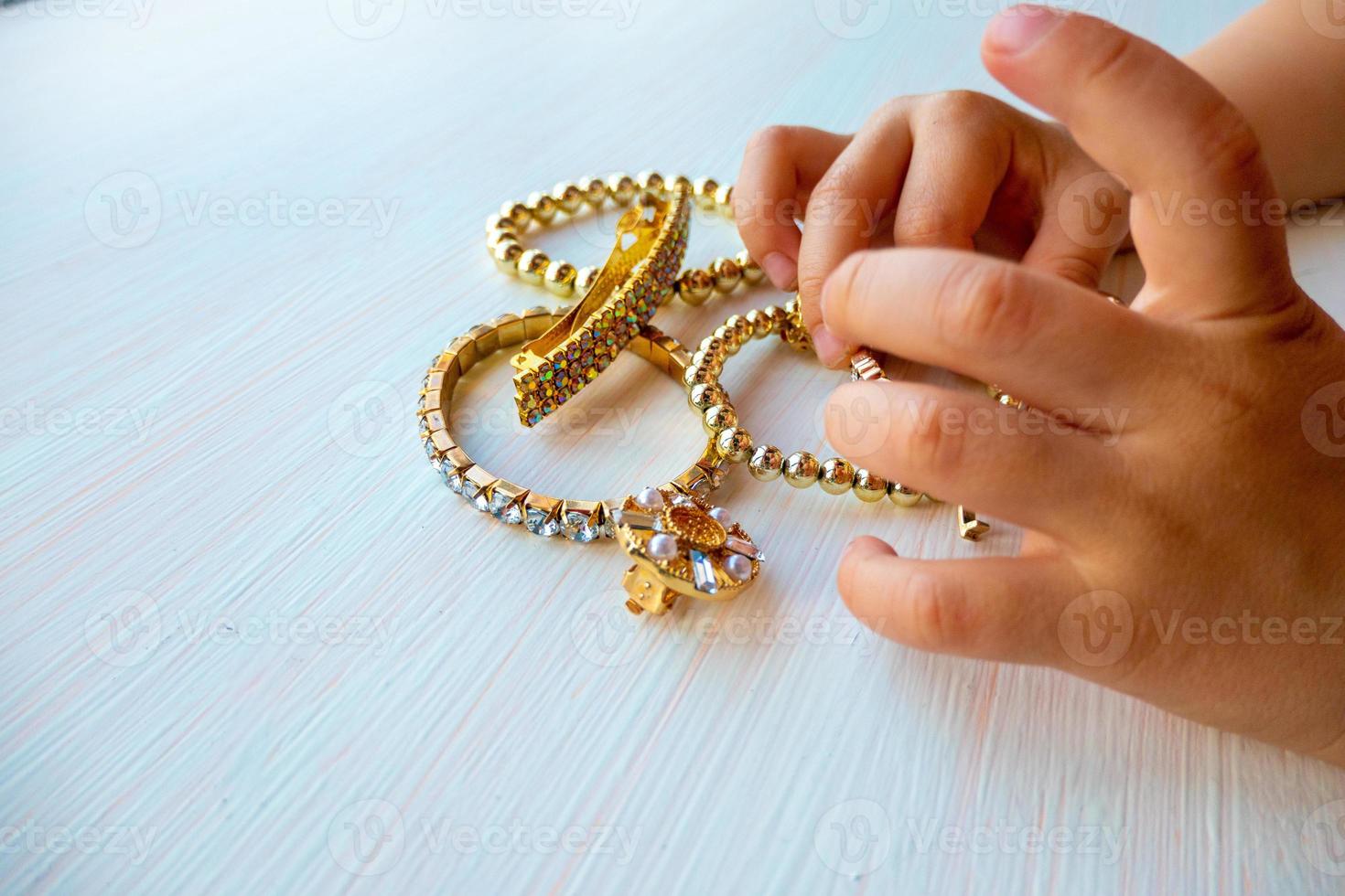les mains des enfants jouent avec des bijoux en or et de la bijouterie, sur fond blanc. concept de bonheur féminin photo