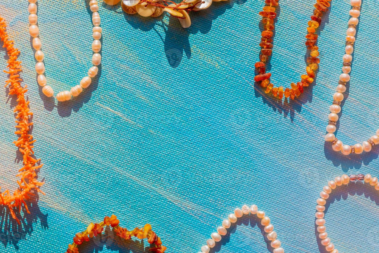 un ensemble de bijoux naturels. espace pour le texte. bijoux de perles et d'os d'ambre de corail sur fond bleu. vue de dessus. photo