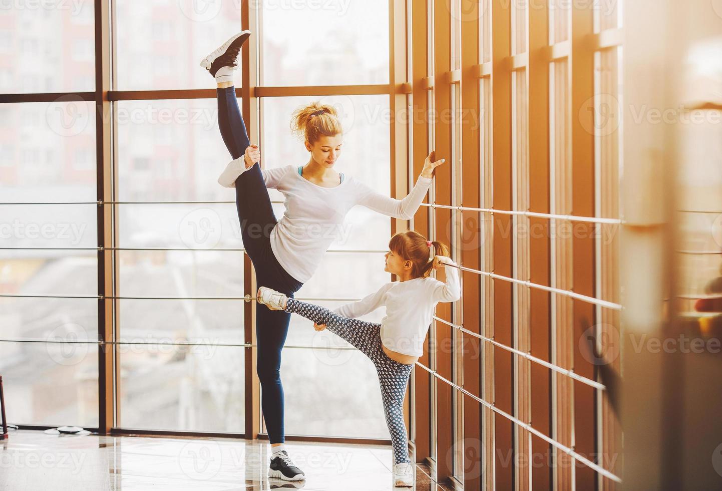 mère apprenant à sa fille à faire un étirement de la jambe haute photo