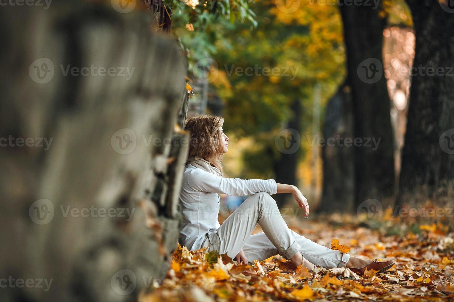 fille assise dans les feuilles d'automne photo