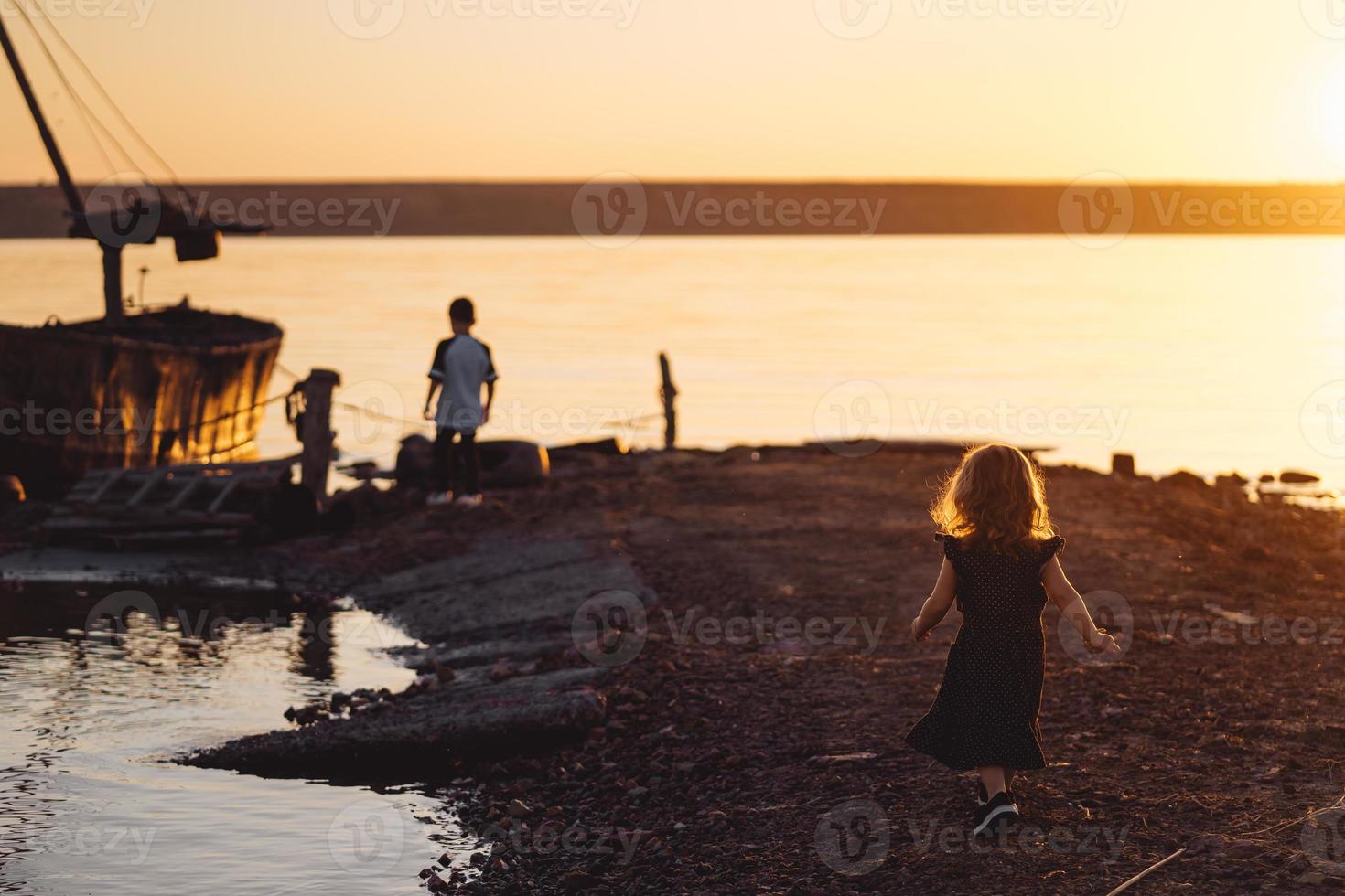 deux enfants marchent le long de la plage, soirée d'été photo