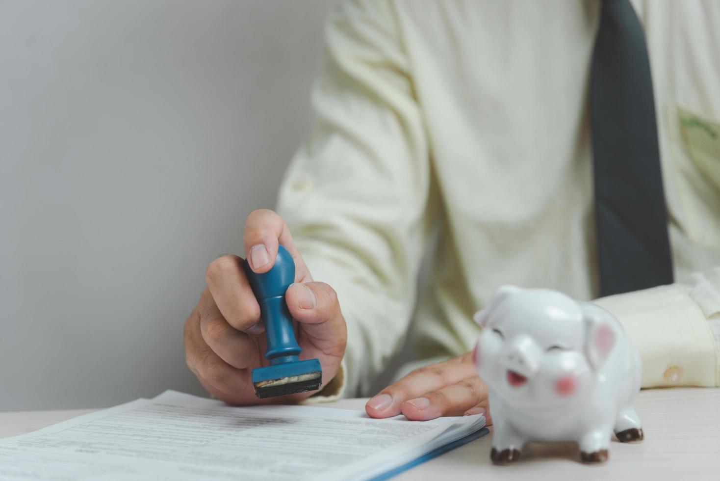 homme tamponnant l'approbation des documents bancaires de financement du travail ou de marketing d'investissement sur le bureau. photo